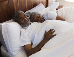 An older couple asleep in bed.