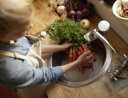 An overhead view of someone washing carrots in a kitchen sink.
