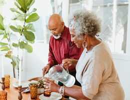 An older couple dishes up a healthy meal together.